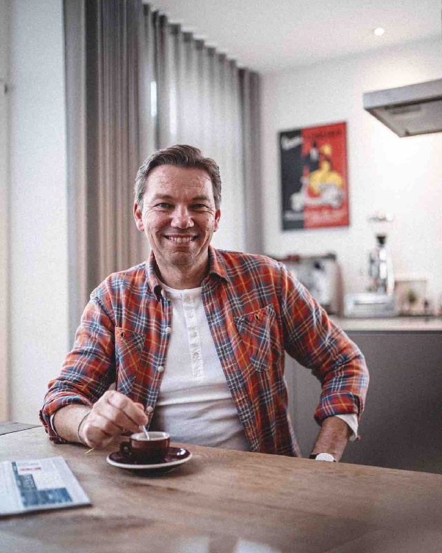 Jochen Bähr sitzt auf einem Sessel mit aufgeschlagenem Buch in der Hand